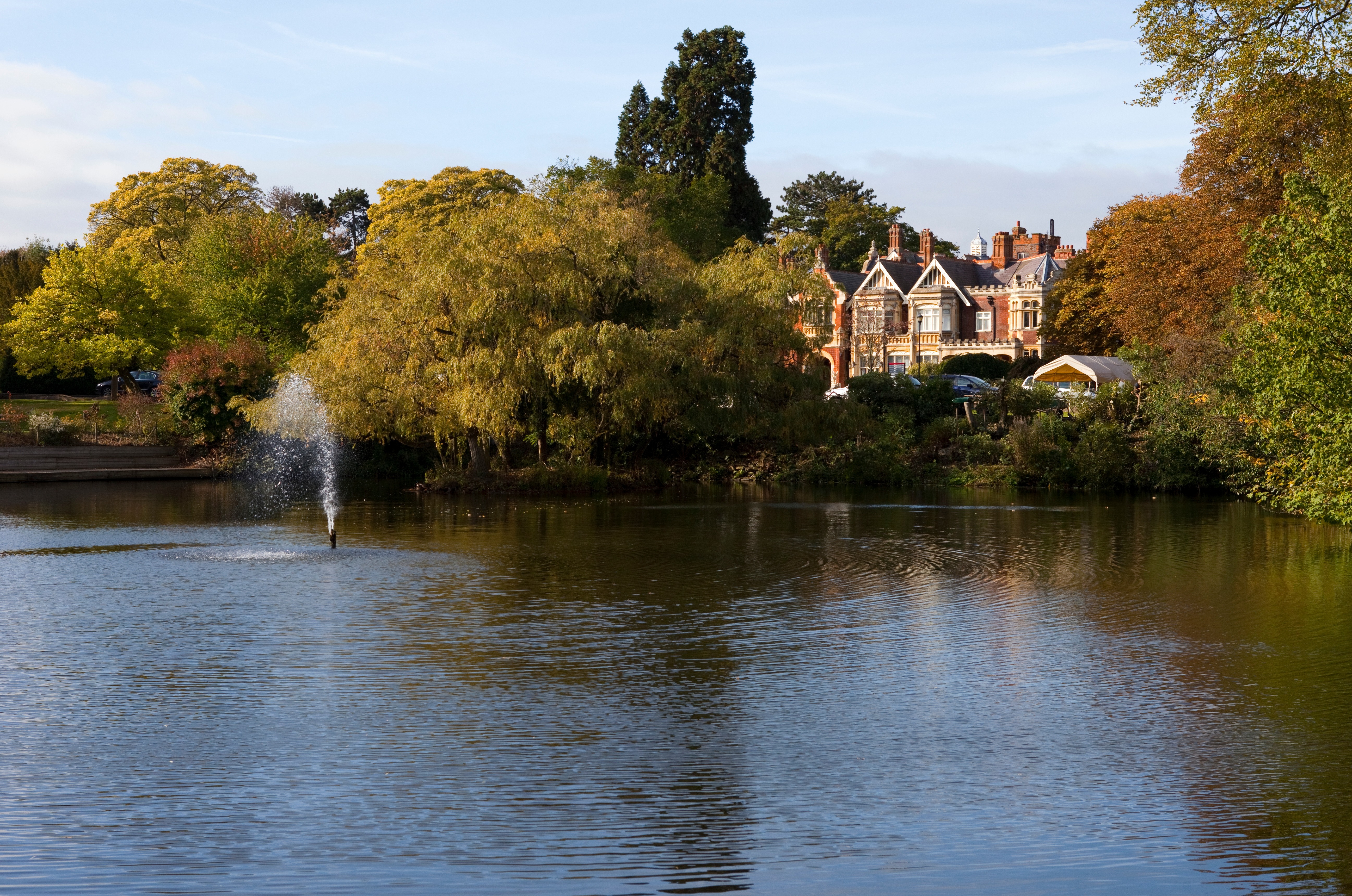Image shows a large lake with a stately home to the rear