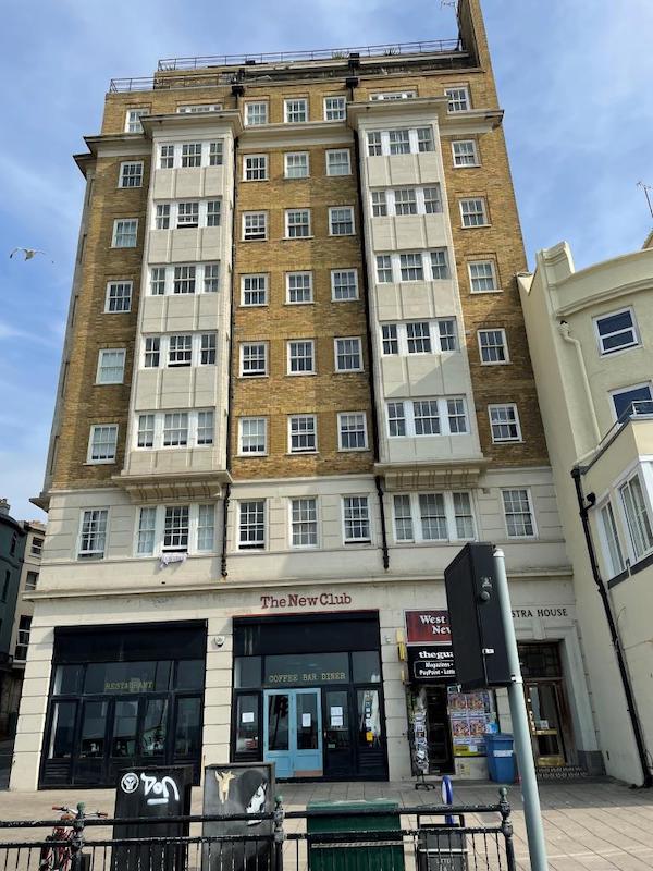 A large retro-style block of flats looms above a shopfront. Lot 127 is on the 2nd floor here