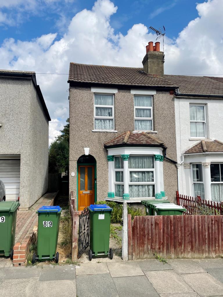 An end of terrace house with a wheelie bin outfront is pictured behind a waist-high fence