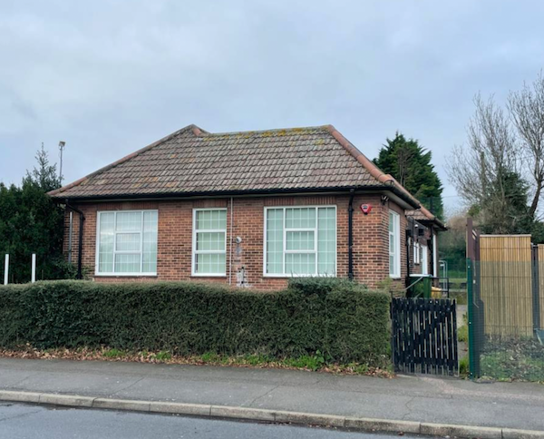 A detached single-story clinical premises is pictured with large windows behind a low hedge