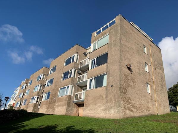 A block of flats with balconies are pictured with blue skies overhead