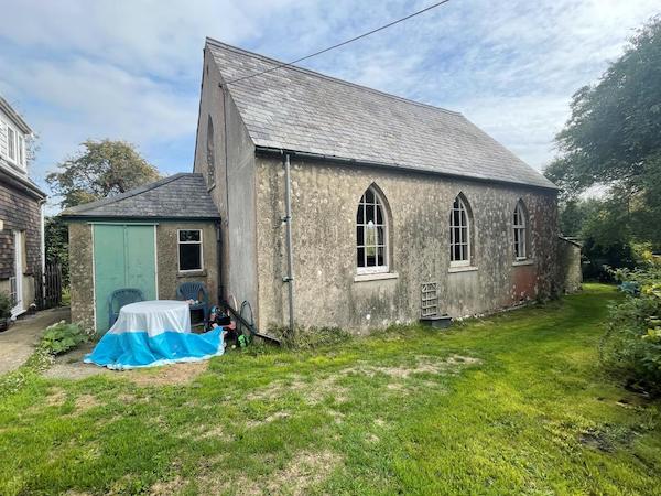 A side view of a church with arched windows and a slated roof