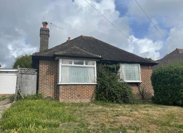 Lot 94, a detached bungalow with large windows, stands with a garden to the front ad ivy climbing up the brickwork